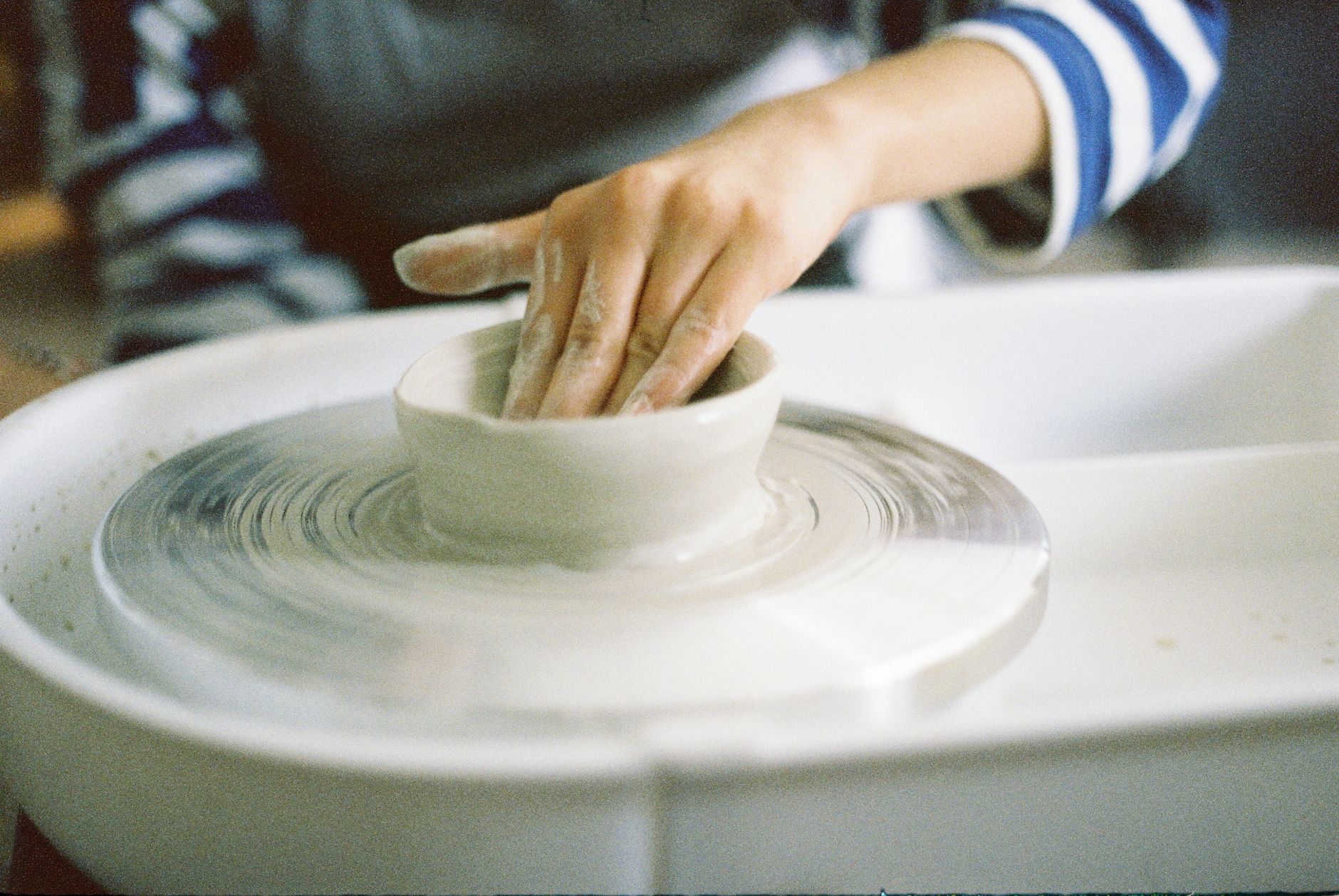 Hands shaping a handmade craft piece on a workbench